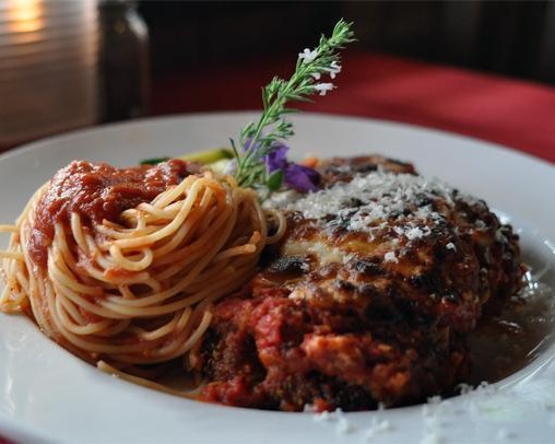 Layers of eggplant parmesan with melted mozzarella and tomato sauce served with spaghetti marinara and seasonal vegetables